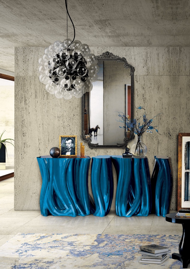 Entryway with a blue table, a big black and white lamp and a big luxury mirror.